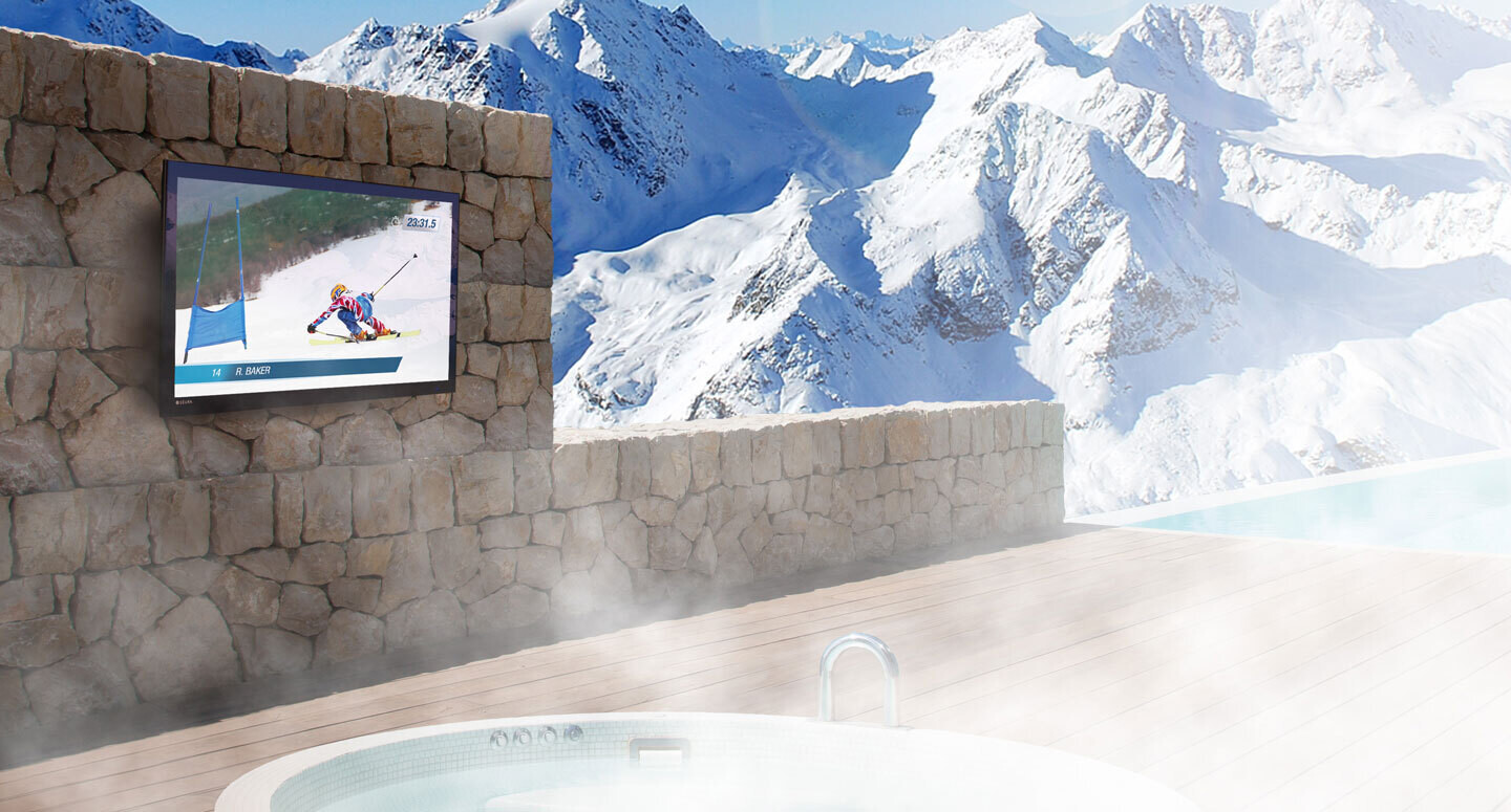 Seura Outdoor TV Mounted on a Stone Wall With Snow Covered Mountains in the Background