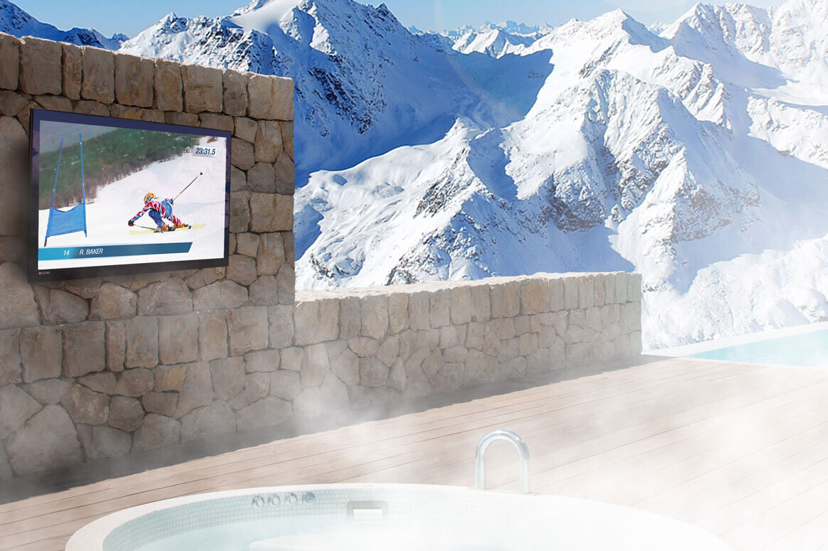 Seura Outdoor TV Mounted on a Stone Wall With Snow Covered Mountains in the Background