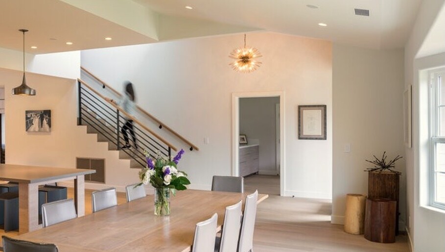 Women in the distance ascends a staircase in a modern home