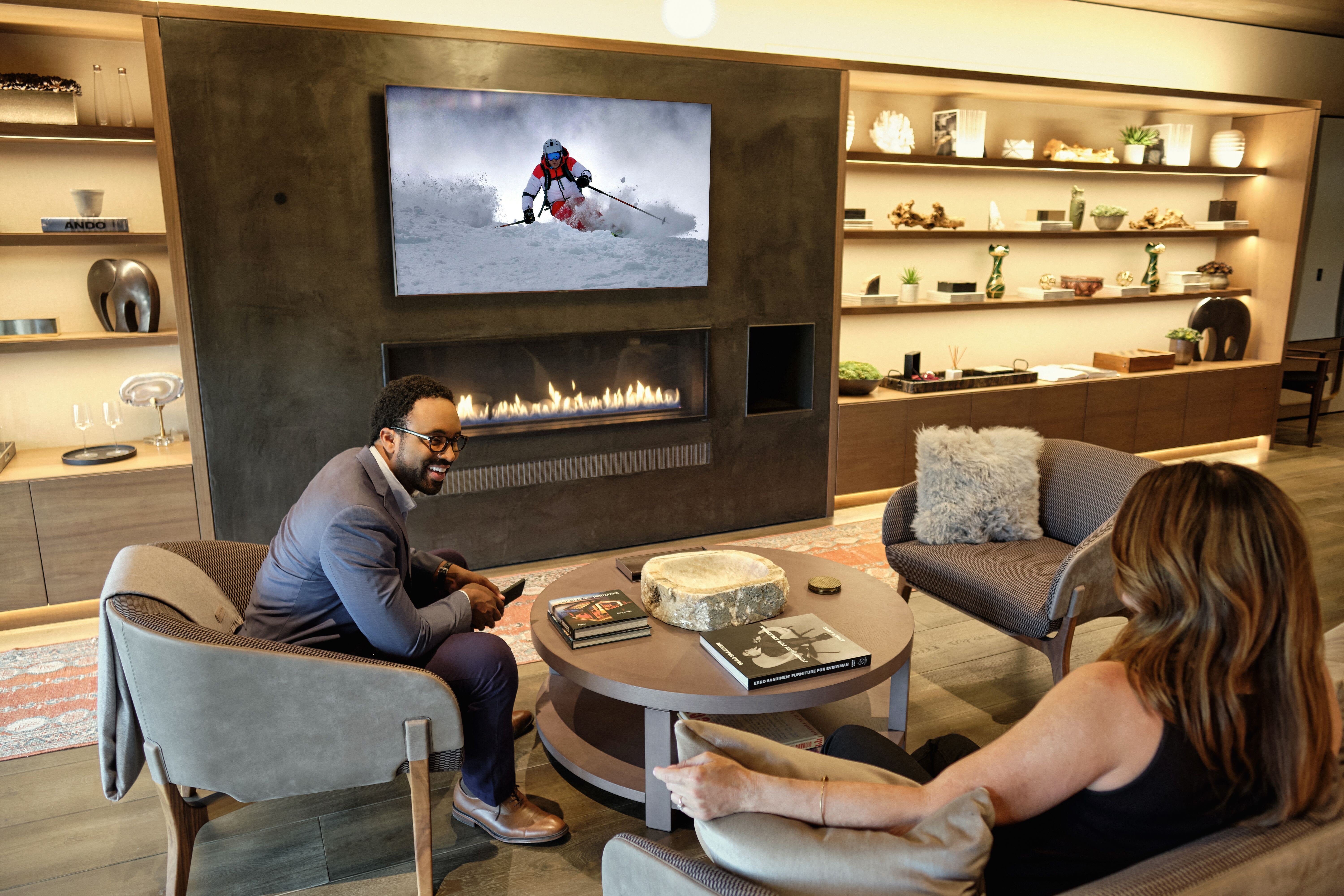 Couple Sitting in a Modern Living Room With Skiing Is Playing On a Seura TV Mirror