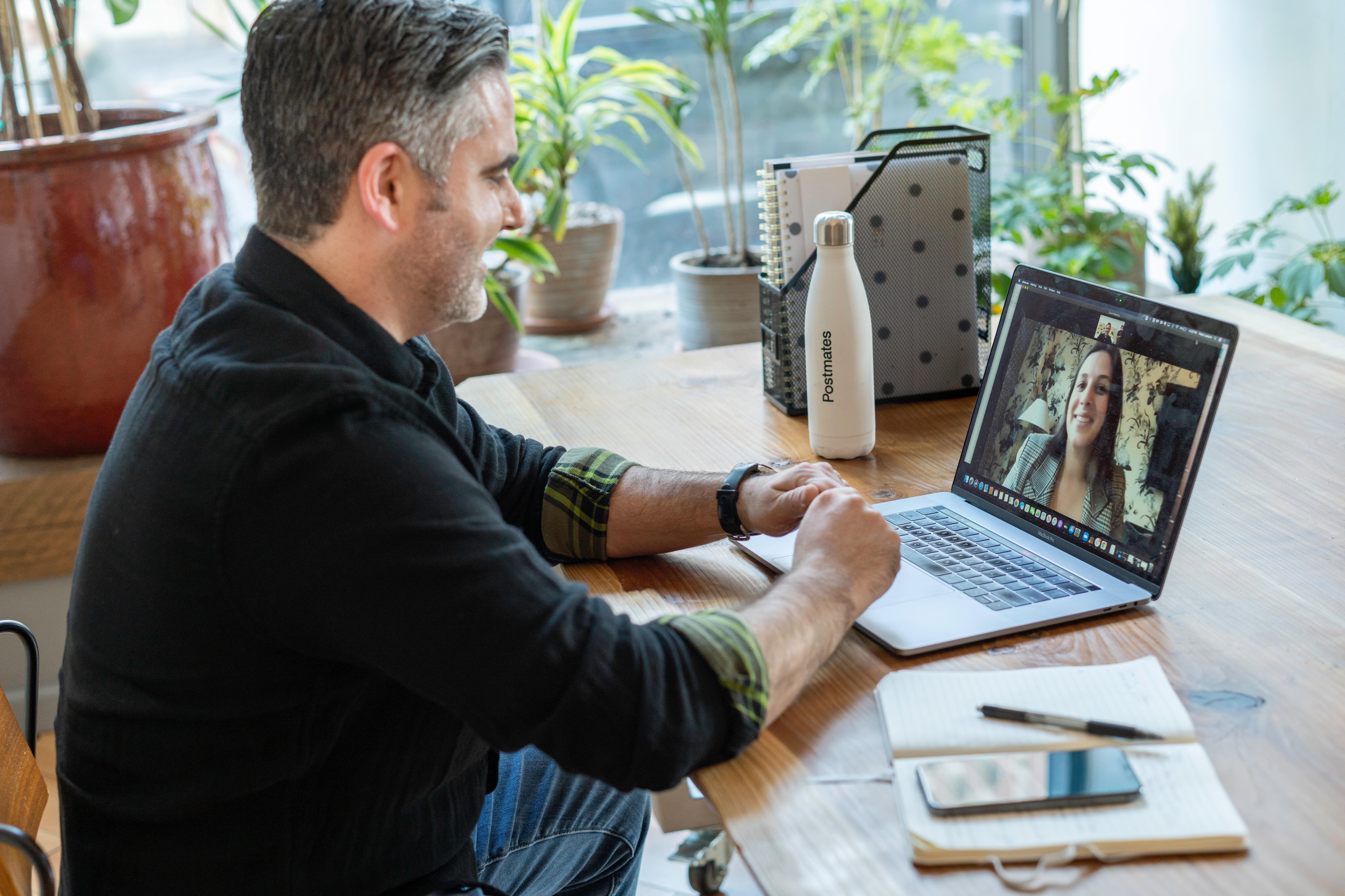 Man Sitting at Wooden Desk Having Video Call With a Women