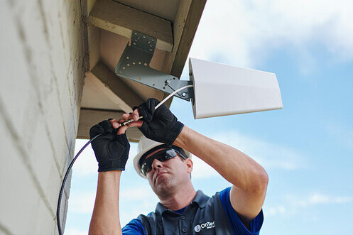 Utility Worker Installing a Cellular Amplification Under Roof Eave
