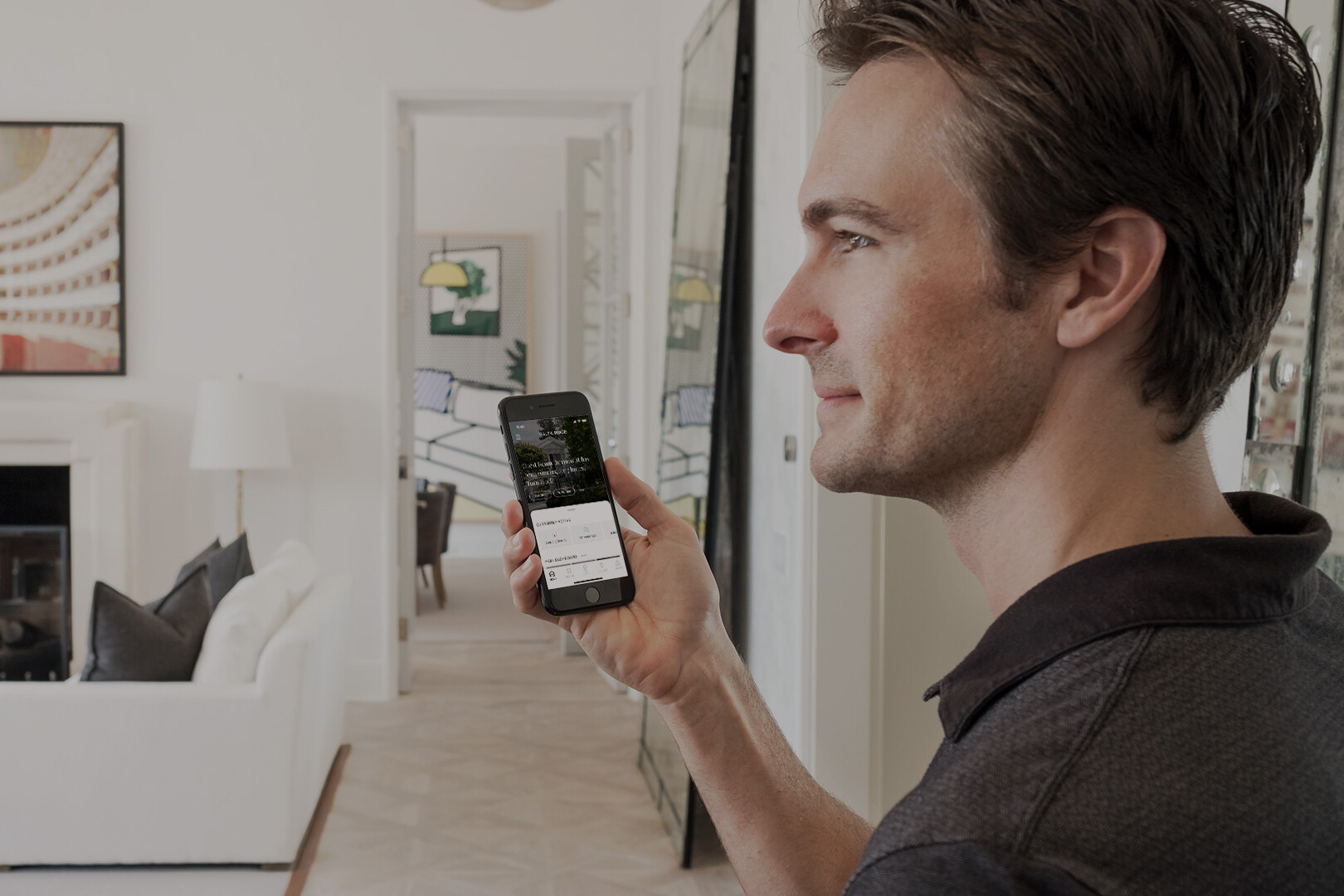 Man In White Living Room Holding Smartphone Managing Indoor Lights