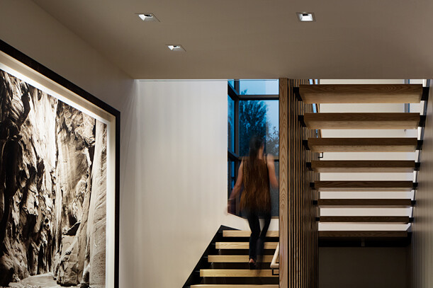 Woman Walking Up Indoor Stairs Accented with Luminaires