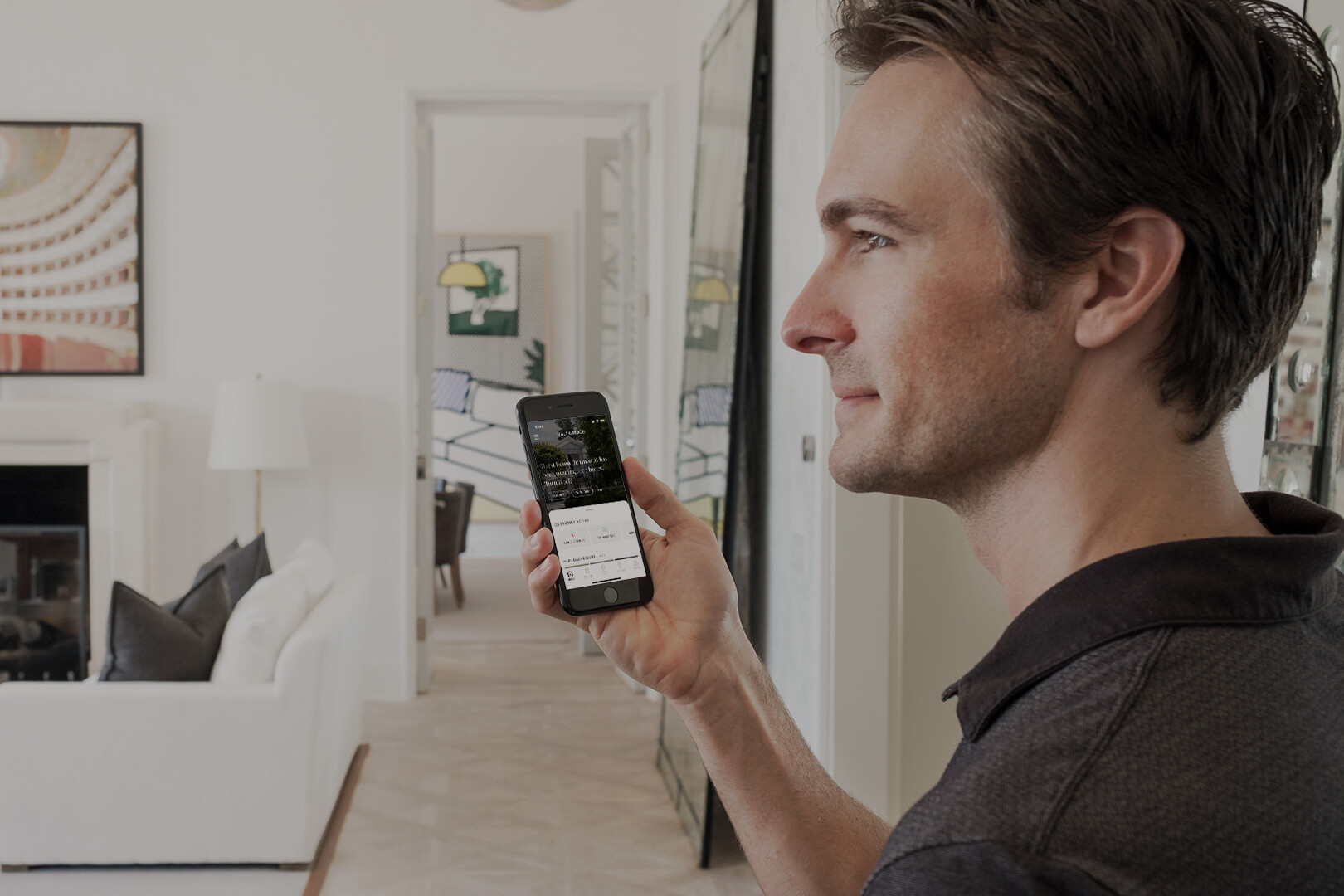 Man In White Living Room Holding Smartphone Managing Indoor Lighting