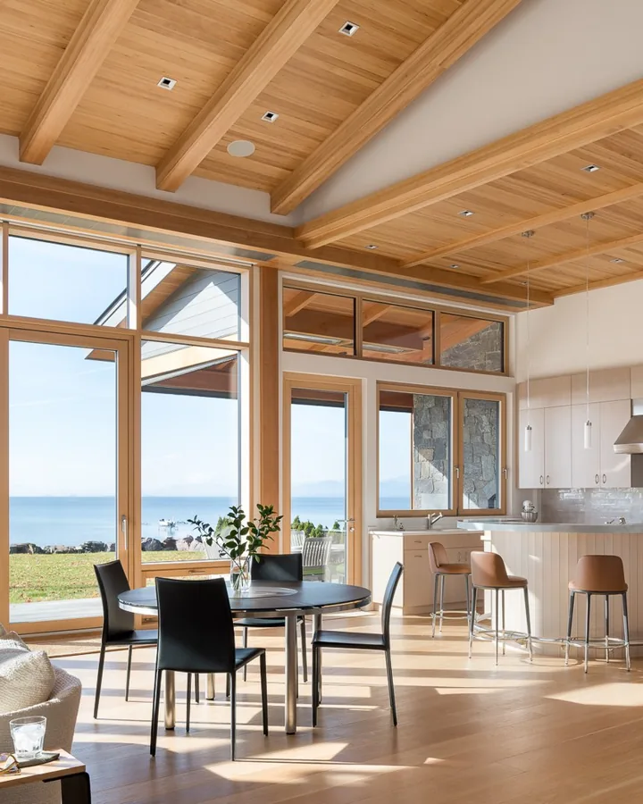 A bright living room with wood ceilings and tall windows facing Lake Champlain