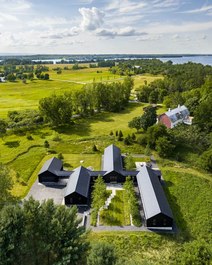 An aerial view of Homestead's gabled buildings in a meadow above Lake Champlain