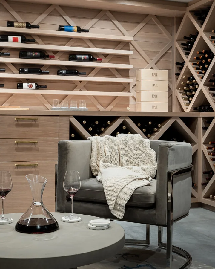 A wine room with diamond racks, a round table and two leather chairs